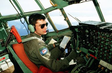 1LT Patrick Piche, 374th Tactical Airlift Wing pilot, surveys the area from the cockpit of his C-130 Hercules aircraft as he flies a Christmas Drop mission. The annual airdrop is a humanitarian effort providing aid to needy islanders throughout Micronesia during the holiday season