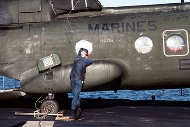 A flight deck crewman aboard the amphibious assault ship USS GUAM (LPH 9) stands by a CH-46E Sea Knight helicopter from Marine Medium Helicopter Squadron 261. The ship is participating in operations off the coast of Lebanon