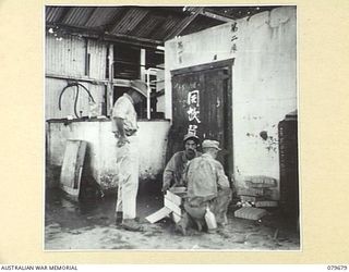 LAE, NEW GUINEA. 1943-10. AMERICAN TROOPS OUTSIDE ONE OF THE FEW BUILDINGS STILL STANDING