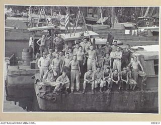 JACQUINOT BAY, NEW BRITAIN. 1945-04-12. PERSONNEL OF 3016 ENGINEER BOAT MAINTENANCE COMPANY (US ARMY), ATTACHED HQ 5 DIVISION LINED UP ON THE END OF ONE OF THEIR REPAIR BARGES