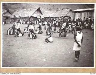 KILA KILA, PAPUA, NEW GUINEA. 1943-12-25. KEREMA BOYS EXECUTING A DANCE AT THE AUSTRALIAN AND NEW GUINEA ADMINISTRATION UNIT NATIVE LABOUR CAMP. THE DANCERS WEAR LONG TRAILS OF GRASS AND FLOWERS, ..