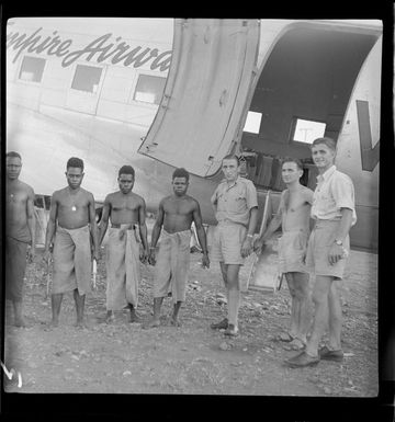 Qantas Lae aircraft service engineers, E Loney, Area Manager, A Priday, ground engineer, and A Nicol, first engineer, with some locals at Lae airfield, Papua New Guinea