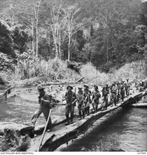 PAPUA, NEW GUINEA. 1942-10. A PATROL OF 2/25TH AND 2/33RD AUSTRALIAN INFANTRY BATTALIONS CROSSING THE BROWN RIVER BY MEANS OF A BRIDGE CONSTRUCTED FROM A FALLEN TREE ON THEIR WAY FORWARD TO MENARI