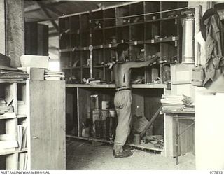 LAE BASE AREA, NEW GUINEA. 1944-12-27. NX97731 SAPPER H.O. PERRATT (1) STOREMAN OF THE 13TH WORKSHOPS AND PARK COMPANY, DOING A STOCK CHECK IN THE 3RD AUSTRALIAN MECHANICAL EQUIPMENT SPARE PARTS ..