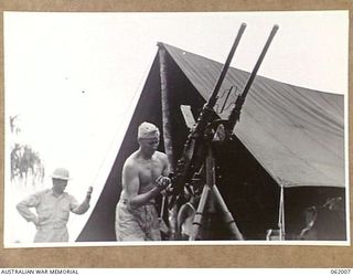 DREGER HARBOUR, NEW GUINEA. 1943-12-05. LIEUTENANT MARK BOTHUM OF MINNESOTA, USA, GROUP ORDNANCE OFFICER, 348TH UNITED STATES FIGHTER GROUP BASE, ASSEMBLING AN ANTI-AIRCRAFT GUN