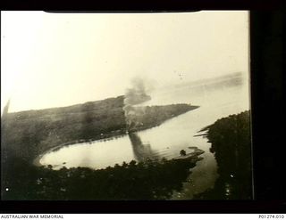 New Britain. 1943. Aerial photograph of a bay showing a Japanese barge burning and sinking near the shore, possibly after strafing by Beaufighter aircraft of No. 30 Squadron RAAF. (Donor K. ..