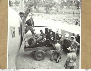 PORT MORESBY, NEW GUINEA. 1943-11-15. TROOPS OF THE 2/5TH AUSTRALIAN FIELD REGIMENT UNLOADING THE PARTS OF A SHORT 25-POUNDER GUN FROM A DOUGLAS AIRCRAFT ONTO A TRAILER, DURING THE UNIT'S MOBILITY ..