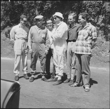 Rally drivers standing with spectators, during the 1st Safari Calédonien racing event, New Caledonia, 1967 / Michael Terry