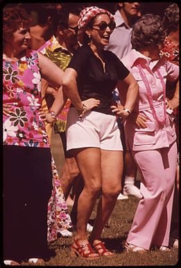 SPIRITED TOURISTS FOLLOW THE MOVEMENTS OF A HULA DANCE DEMONSTRATOR