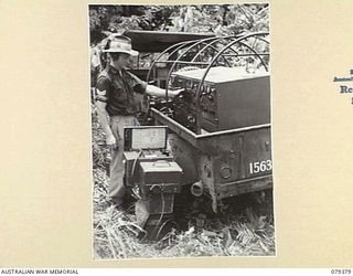 LAE, NEW GUINEA. 1945-03-11. QX39369 CORPORAL G.C. FINDLAY, 34TH WIRELESS SECTION (HEAVY) 19TH LINES OF COMMUNICATION SIGNALS OPERATING A TRAILER BORNE WS133 TRANSMITTER IN THE JUNGLE