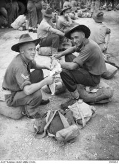 CORPORAL R. A. MOBBS OF NORTH PARRAMATTA, NSW, (LEFT), AND SAPPER J. H. BARRETT OF COTTESLOE, WA, (RIGHT), MEMBERS OF 7 MECHANICAL EQUIPMENT COMPANY, SITTING WITH THEIR GEAR AS THEY WAIT THEIR TURN ..