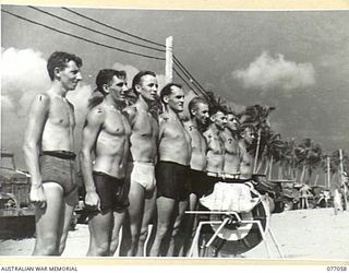 TOROKINA, BOUGAINVILLE, 1944-11-19. MEMBERS OF THE ROYAL NEW ZEALAND AIR FORCE SURF LIFE SAVING TEAM LINED UP BEHIND THEIR REEL AFTER WINNING THE EVENT AT THE SURF CARNIVAL ORGANISED BY ..