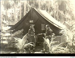 MADANG, NEW GUINEA. 1944-06-17. VX106327 LIEUTENANT R. L. MATHEWS, ADJUTANT (LEFT), AND NX114337 LIEUTENANT F. J. NORRIE OUTSIDE THEIR OFFICE AT HEADQUARTERS, 58/59TH INFANTRY BATTALION