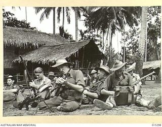 1943-07-28. NEW GUINEA. AUSTRALIANS CLEANING BREN GUNS AND RIFLES IN A DESERTED NATIVE VILLAGE NEAR MUBO. WITH AMERICANS WHO LANDED AT NASSAU BAY THEY DROVE THEJAPS FROM MUBO CAUSING 950 CASUALTIES ..