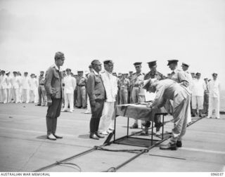 AT SEA OFF RABAUL, NEW BRITAIN. 1945-09-06. THE SURRENDER CEREMONY ON BOARD THE AIRCRAFT CARRIER HMS GLORY, SHOWING LIEUTENANT GENERAL V.A.H. STURDEE, GENERAL OFFICER COMMANDING FIRST ARMY, SIGNING ..