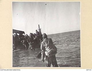 WEWAK AREA, NEW GUINEA. 1945-09-21. MAJOR GENERAL K. ARAKI BEING CARRIED PICK- A- BACK BY HIS BATMAN THROUGH THE SURF TO A LANDING BARGE. MEMBERS OF 18 JAPANESE ARMY, ARE BEING TRANSFERRED UNDER ..