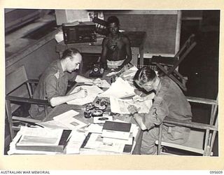 LAE AREA, NEW GUINEA. 1945-08-31. THE EDITORIAL ROOM OF THE ARMY NEWSPAPER, GUINEA GOLD, WHICH IS EDITED AND PRINTED AT "CHARING CROSS" IN THE LAE BASE. COPY IS CALLED FROM THE RADIO BEAM WIRELESS ..