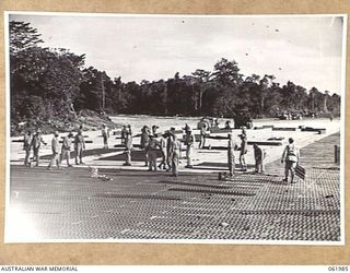 DREGER HARBOUR, NEW GUINEA. 1943-12-03. ENGINEERS OF THE 870TH UNITED STATES AVIATION ENGINEER BATTALION LAYING STEEL SECTIONS FOR A NEW LANDING STRIP WHICH WILL BE 6000 FEET LONG AND 110 FEET WIDE ..