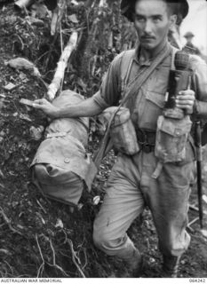 FINISTERRE RANGES, NEW GUINEA. 1944-01-23. QX38244 PRIVATE J.T. CARRIGAN OF "D" COMPANY, 2/9TH INFANTRY BATTALION WITH A "BLOCKBUSTER" WHICH IS USED FOR BLASTING ENEMY PILLBOXES. IT CONSISTS OF A ..