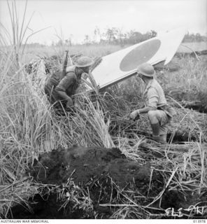 1942-12-05. PAPUA. ALLIES ATTACK BUNA. ONE OF THE ZERO FIGHTER AIRCRAFT HIT BY THE ALLIED AIR FORCE ON THE AIR STRIP AT BUNA. THESE WERE THE FIRST PICTURES EVER TAKEN OF THE NEW TYPE OF ZERO ..