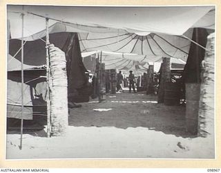 BORAM, NEW GUINEA. 1945-11-21. DAMAGED PARACHUTES FORMING A ROOFED PASSAGE IN THE TENT LINES OF 30 INFANTRY BATTALION