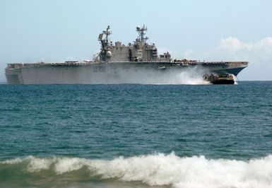 The US Navy (USN) Landing Craft Air-Cushioned Craft (LCAC-72) craft, assigned to Assault Craft Unit Five (ACU-5), moves away from the Tarawa Class Amphibious Assault Ship, USS PELEIU (LHA 5), as it heads toward the beach at the Pacific Missile Range Facility, on the island of Kauai, Hawaii (HI), while conducting amphibious training