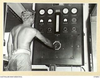 LAE, NEW GUINEA. 1944-11-15. NX171210 CRAFTSMAN A.J. STONHAM, 2/7TH ADVANCED WORKSHOPS, WORKING ON THE MAIN INSTRUMENT PANEL OF THE ONLY AUSTRALIAN OXYGEN GENERATING PLANT IN NEW GUINEA