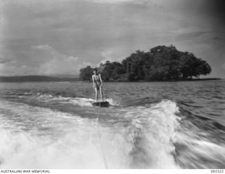 JACQUINOT BAY, NEW BRITAIN, 1945-05-20. CORPORAL E.M. BIRCHALL, AUSTRALIAN ARMY MEDICAL WOMEN'S SERVICE, 2/8 GENERAL HOSPITAL, DEMONSTRATING THE ART OF AQUAPLANING IN AN EXHIBITION DURING THE GRAND ..