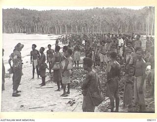 MUSCHU ISLAND, NEW GUINEA. 1945-09-11. MUSCHU ISLAND NATIVES LINED UP ON THE BEACH WITH ALL THEIR BELONGINGS AWAITING TRANSFER TO THE NEW GUINEA MAINLAND, WHERE THEY ARE TO BE REHABILITATED BY ..
