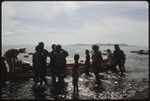 People on beach taking goods to a boat