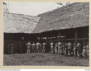 LAE, NEW GUINEA, 1945-05-09. HEADQUARTERS FIRST ARMY TROOPS, UNABLE TO FIND ROOM INSIDE THE GARRISON CHAPEL, JOIN THE HYMN SINGING FROM OUTSIDE. THE MEN ARE ATTENDING THE CHURCH OF ENGLAND AND ..