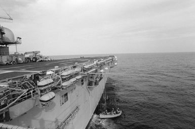 Crew members prepare to hoist in a boat alongside the amphibious assault ship USS GUAM (LPH 9) during the field training Exercise SOLID SHIELD'87