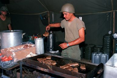 SPEC. 5 Angel Rios, 25th Infantry Division, prepares a steak dinner in the Service Battery's field kitchen. The meal is for troops participating in live-fire artillery exercises at the U.S. Army's Pohakuloa Training Area