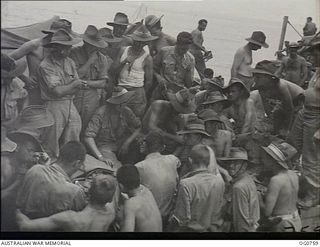 AT SEA IN ADMIRALTY ISLANDS AREA. 1944-03-08. A MEDICAL OFFICER, FLIGHT LIEUTENANT R. C. WILLIS, MELBOURNE, VIC, IS GIVING A TALK ON TROPICAL HYGIENE TO RAAF REINFORCEMENT TROOPS ON A LANDING CRAFT ..