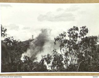 DONADABU AREA, NEW GUINEA. 1943-11-30. THE OBJECTIVE, WREATHED IN SMOKE FROM EXPLODING 25-POUNDER SHELLS PRIOR TO THE ATTACK BY THE INFANTRY DURING A COMBINED EXERCISE BY THE 2/10TH AUSTRALIAN ..