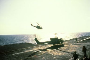 A UH-1N helicopter approaches for a landing on the flight deck of the amphibious assault ship USS GUAM (LPH-9) as another UH-1N prepares to take off. The helicopters are participating in flight operations off the coast of Beirut, Lebanon