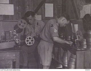 KOITAKI, NEW GUINEA. 1943-07-13. PROJECTIONISTS WORKROOM OF THE AUSTRALIAN ARMY EDUCATION SERVICE CENTRE AT SEVENTEEN MILE. SHOWN ARE:- V210648 CORPORAL E. W. JENSEN (LEFT) AND NX144078 SERGEANT L. ..