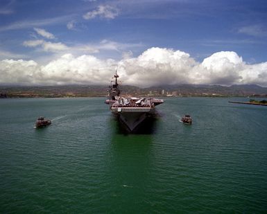 Sailors man the rails aboard the aircraft carrier USS RANGER (CV-61) as the large harbor tugs TUSKEGEE (YTB-806) and WAXAHATCHIE (YTB-814) escort the vessel in preparation for assisting it in docking. The RANGER is stopping off at Pearl Harbor while en route to its home port after returning from deployment in the Persian Gulf during Operation Desert Storm