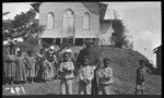 Children, priest and nun in front of church at Dilava mission