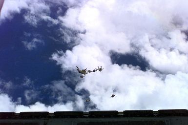 Rear view long shot from the rear entrance of a USAF C-130 Hercules Cargo aircraft at US Marines from Company A, 5th Reconnaissance Battalion, 3rd Marines, as they've just jumped from the plane with their MC5 Freefall Square Parachutes at 9-thousand feet above the ground during Force Reconnaissance Exercises over Andersen Air Force Base, Guam