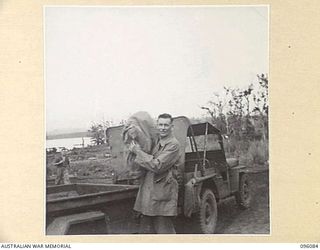 CAPE WOM, WEWAK AREA, NEW GUINEA. 1945-09-06. CORPORAL R.G. JOYCE, 6 DIVISION POSTAL UNIT, UNLOADING MAIL AT A UNIT POST OFFICE