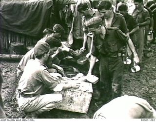 THE SOLOMON ISLANDS, 1945-03-27. AUSTRALIAN SERVICEMEN BEING SERVED WITH A MEAL AT A CAMPSITE ON THE NUMA NUMA TRAIL ON BOUGAINVILLE ISLAND. (RNZAF OFFICIAL PHOTOGRAPH.)