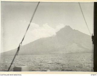 MANAM ISLAND, NEW GUINEA. 1944-09-03. THE 4265 FEET HIGH ACTIVE VOLCANO SEEN THROUGH THE EARLY MORNING MIST AS THE MEDICAL LAUNCH, AM1568 OF THE 4TH SEA AMBULANCE TRANSPORT COMPANY APPROACHES THE ..