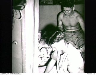 THE SOLOMON ISLANDS, 1945. VIEW INSIDE A RAAF AIRCRAFT SHOWING TWO SERVICEMEN WITH PAMPHLETS TO BE DROPPED TO THE JAPANESE FORCES ON BOUGAINVILLE ISLAND. (RNZAF OFFICIAL PHOTOGRAPH.)