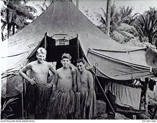 MILNE BAY, PAPUA, C. 1943-05. THREE ARMOURERS WITH NO. 100 SQUADRON RAAF POSING IN NATIVE GRASS SKIRTS OUTSIDE THEIR TENT, KNOWN AS "THE COCKIES' DEN", AT GURNEY AIRFIELD. LEFT TO RIGHT: IAN ..