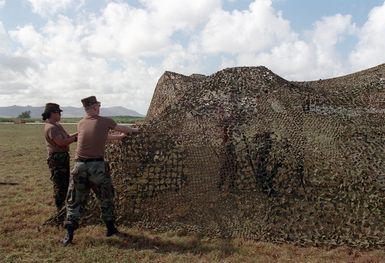 US Army, (USA) personnel assigned to the 21st Signal Battalion, Fort Richardson, Alaska place the finishing touches on camouflaged netting use to cover the communication center at Orote Point, Guam during Exercise TANDEM THRUST 99