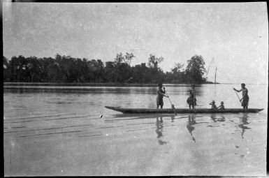 Three people standing and paddling with two children seated in a canoe, Ramu River, New Guinea, 1935 / Sarah Chinnery