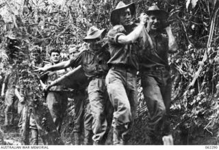 Shaggy Ridge, New Guinea. 1943-12-27. Stretcher bearers of the 2/16th Australian Infantry Battalion, 21st Australian Infantry Brigade, moving along a jungle track to the Regimental Aid Post with ..