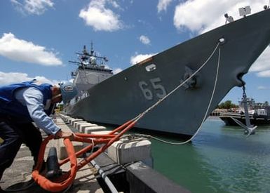 US Navy (USN) Boatswain's Mate Third Class (BM3) Davian Begay removes a mooring line from a dock cleat for cast off as the USN Ticonderoga Class Guided Missile Cruiser USS CHOSIN (CG-65) departs Naval Station (NS) Pearl Harbor for a regularly scheduled deployment. The CHOSIN is deploying as part of Expeditionary Strike Group One (ESG-1) in support of the Global War on Terrorism (GWOT)