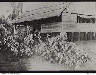 KIKORI, PAPUA, C. 1942. BUILDING USED AS A SPOTTING STATION BY MEMBERS OF THE NEW GUINEA AIR WARNING WIRELESS COMPANY (NGAWW), WITH FOUR STAFF MEMBERS STANDING IN FRONT